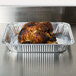 A large cooked chicken in a Western Plastics foil tray.