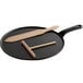 A black Chasseur cast iron crepe pan with a wooden spatula and scraper on a black tray.