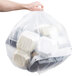 A hand holding a clear plastic bag full of white plastic containers.