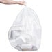 A person holding a large clear plastic bag full of white trash.