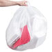 A hand holding a Berry clear plastic trash bag filled with white objects.