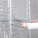 A person holding a clear plastic cover over a bun pan rack.