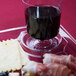 A clear plastic square plate with a cup holder holding crackers and a glass of wine.