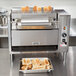 An APW Wyott vertical conveyor bun grill toaster with bread toasting.