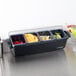 A San Jamar condiment bar with 4 compartments holding fruit and a glass.