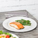 A Tuxton AlumaTux Pearl White china plate with a piece of salmon and green beans on a table.