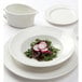A Tuxton AlumaTux white china plate with a salad and radish slices on it.