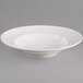A Tuxton white china bowl with a rim on a gray surface.