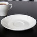 A Tuxton Modena AlumaTux Pearl White saucer with a cup of coffee on it.