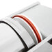 A close up of a stainless steel and red Tre Spade sausage stuffer cylinder.
