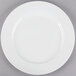 A Tuxton AlumaTux Pearl White china plate with a white rim on a gray surface.