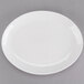 A white Tuxton oval china platter with a rim on a gray surface.