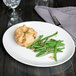 An oval Tuxton china platter with a meat pie and green beans on it.