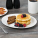 A Tuxton oval china platter with pancakes, sausage, and berries on a table.