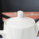 A Tuxton AlumaTux white china coffee pot lid on a white teapot.