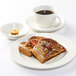 A plate of french toast and a Tuxton Modena AlumaTux Pearl White Demitasse saucer with a cup of coffee on it.