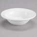 A white Tuxton China fruit bowl on a white surface.