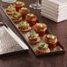 An American Metalcraft hammered stainless steel tray with appetizers on a table.