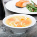 A Tuxton bright white china bowl filled with soup with noodles and carrots.