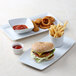 A TuxTrendz rectangular china tray with a hamburger, fries, and ketchup on a table.