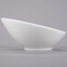 A close-up of a Tuxton bright white china bowl with a curved edge.