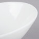 A close-up of a Tuxton Bright White slanted china bowl with a curved edge.