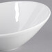 A Tuxton TuxTrendz bright white china bowl with a slanted rim.