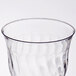 A close up of a Fineline clear plastic wine goblet with a wavy design.