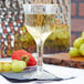 A clear plastic wine goblet filled with white wine and fruit on a table.