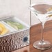 An American Metalcraft stainless steel condiment bar with lemons and a martini glass with olives.