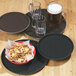 A Carlisle black non-skid fiberglass serving tray holding a bowl of cereal and a glass of beer.