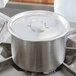 A silver Vollrath double boiler pot with a lid on a stove.