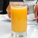A Libbey juice glass filled with orange juice on a table.