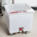 A white Cambro vegetable crisper container with a clear lid holding red tomatoes.