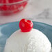 A scoop of white ice cream with a Regal Maraschino cherry on top.