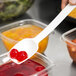 A person using a Thunder Group white polycarbonate salad bar spoon to serve red cherries over a bowl of fruit.
