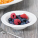 A bowl filled with blueberries and raspberries on a table with a fork.