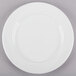 A Tuxton AlumaTux Pearl White china plate with a circular rim on a gray surface.