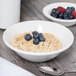A Tuxton AlumaTux china bowl filled with oatmeal and blueberries on a table.