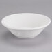 A Tuxton San Marino AlumaTux white China grapefruit bowl with a small rim on a gray surface.