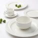 A group of white Tuxton AlumaTux China stackable soup cups and plates.