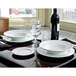 A table set with Tuxton AlumaTux Pearl White plates and wine glasses.