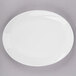 A Tuxton San Marino AlumaTux Pearl White oval platter with a white rim on a gray surface.
