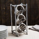 A silver Cal-Mil flatware display rack with three vertical cylinders holding utensils.