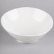 A Tuxton AlumaTux Pearl White slant bowl on a gray surface.