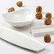 A rectangular white china plate with nuts and a bowl.