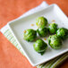 A Tuxton AlumaTux Pearl White square china plate with brussels sprouts.