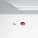 The silver surface of a Hatco Glo-Ray merchandiser with a red button in a hole.