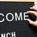 A person using an Aarco Helvetica letter board to display the words "Welcome Lunch"