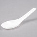A WNA Comet white plastic Asian soup spoon on a gray surface.